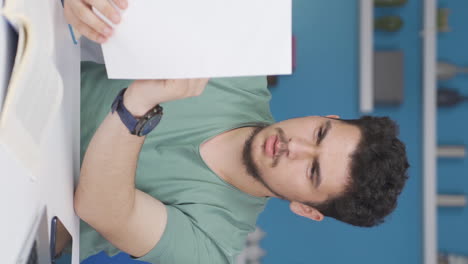 Vertical-video-of-Male-student-working-between-paper-and-laptop.